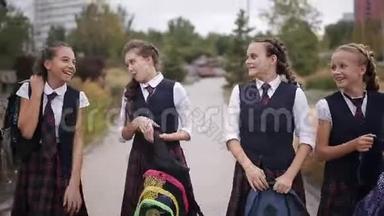 穿着同样校服的女学生背着背包在公园里嬉笑<strong>打闹</strong>